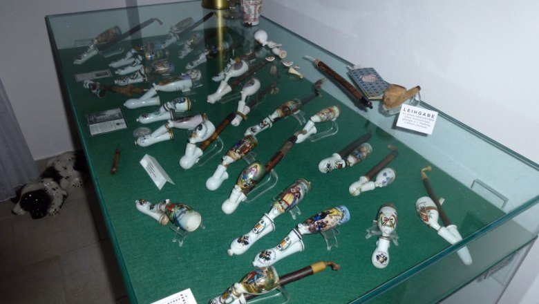 Pfeiffenmuseum, © Marktgemeinde St. Aegyd/Neuwalde Vitrine mit dekorativen Pfeifen in einem Museum.
