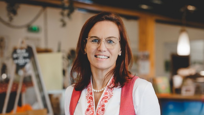 Wirtin Christiane Rabl, © Niederösterreich Werbung/ David Schreiber Frau in traditioneller Tracht serviert ein Gericht in einem Restaurant.