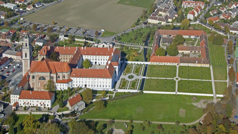 Flugaufnahme, © Hans Kopitz Luftaufnahme eines großen Gebäudekomplexes mit roten Dächern und Gartenanlagen.