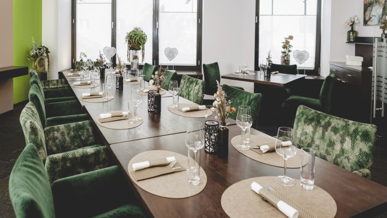 Elegantes Restaurant mit grünen Stühlen und gedecktem Tisch.