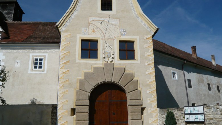 Eingangstor von Schloss Kreisbach mit Sonnenuhr und Wappen.