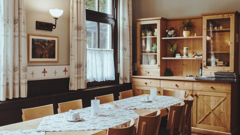 Gem&uuml;tlicher Gastraum mit Holzm&ouml;beln und Tischdecken.