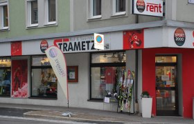 Au&szlig;enansicht eines Sportgesch&auml;fts namens Strametz mit Skiern und Sportbekleidung im Schaufenster.