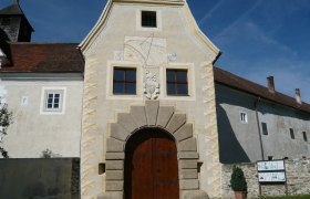 Eingangstor von Schloss Kreisbach mit Sonnenuhr und Wappen.